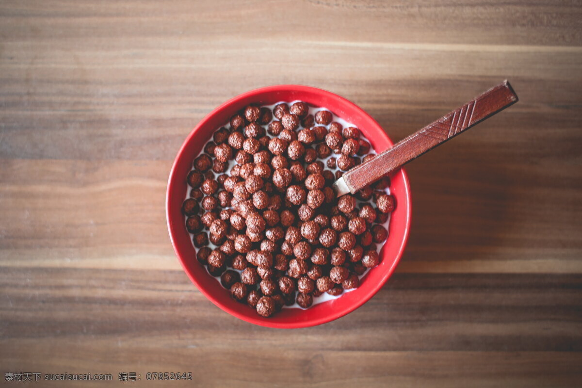 巧克力豆 巧克力 巧克力球 牛奶 谷物 木柄勺子 红碗 木桌 木纹 营养 早餐 闲食 甜点 美食 食物 生活休闲 餐饮美食图片 餐饮美食 西餐美食
